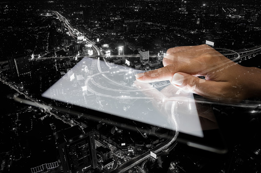 double exposure hand using tablet and city on night background tech trends